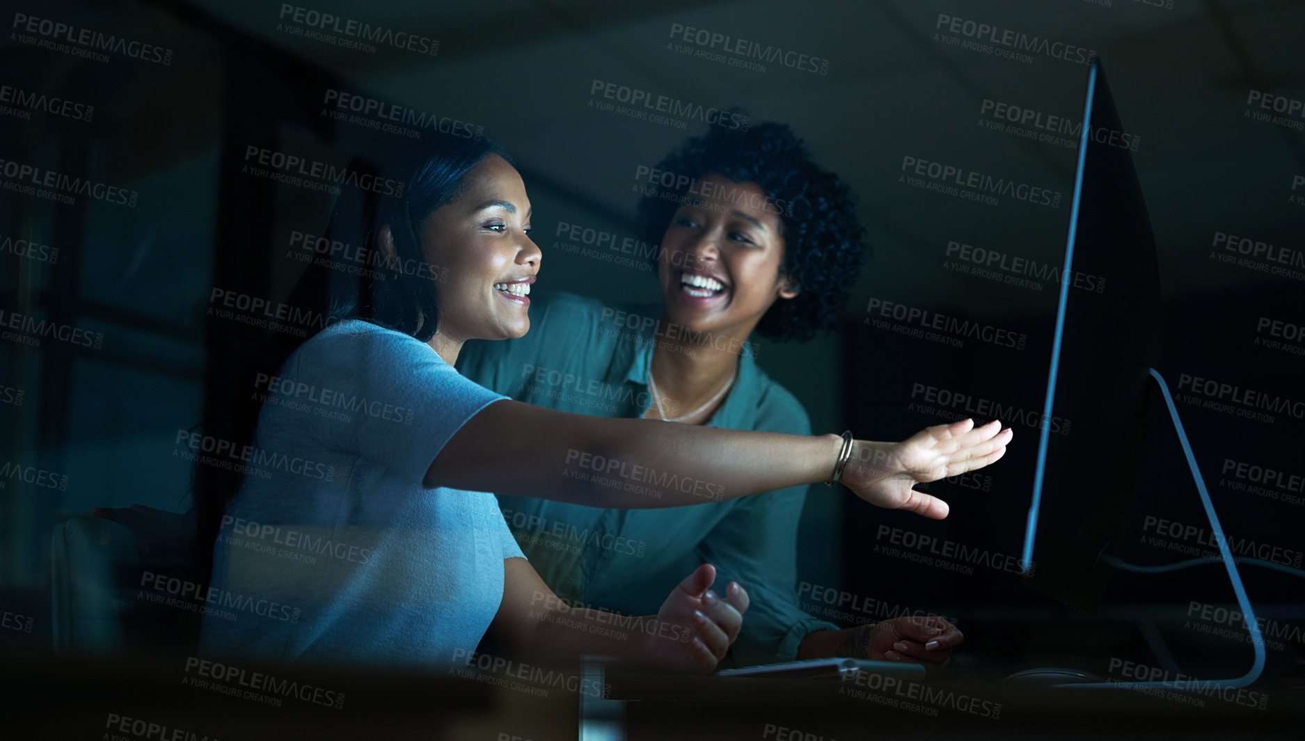 Buy stock photo Shot of two young businesswomen using a computer together during a late night at work