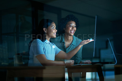 Buy stock photo Shot of two young businesswomen using a computer together during a late night at work