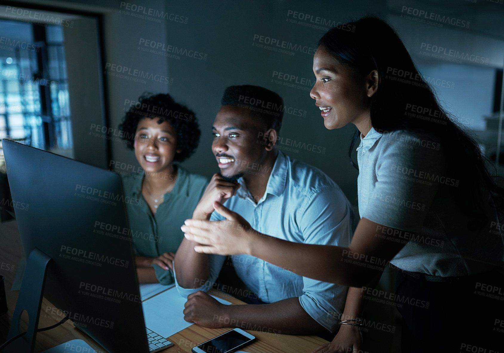 Buy stock photo Shot of a group of young businesspeople using a computer together during a late night at work