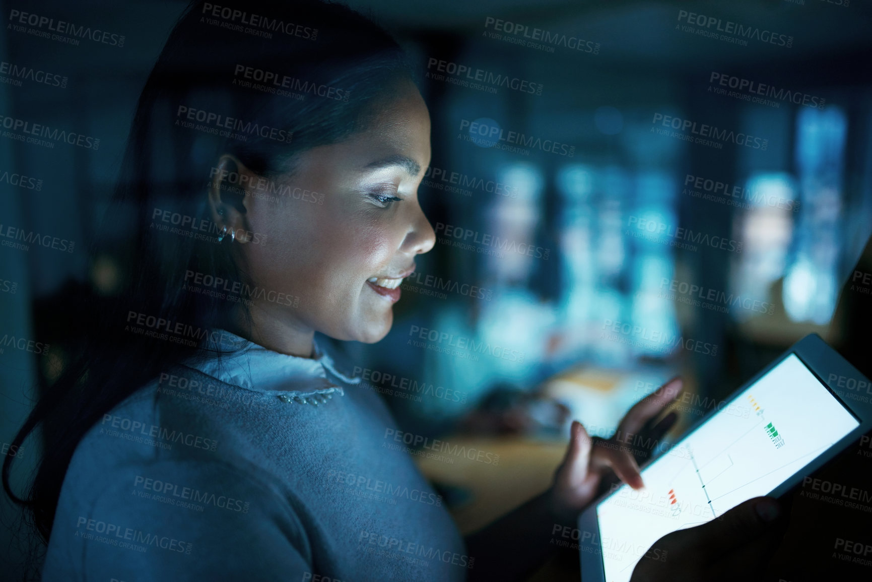 Buy stock photo Shot of a young businesswoman using a digital tablet during a late night at work