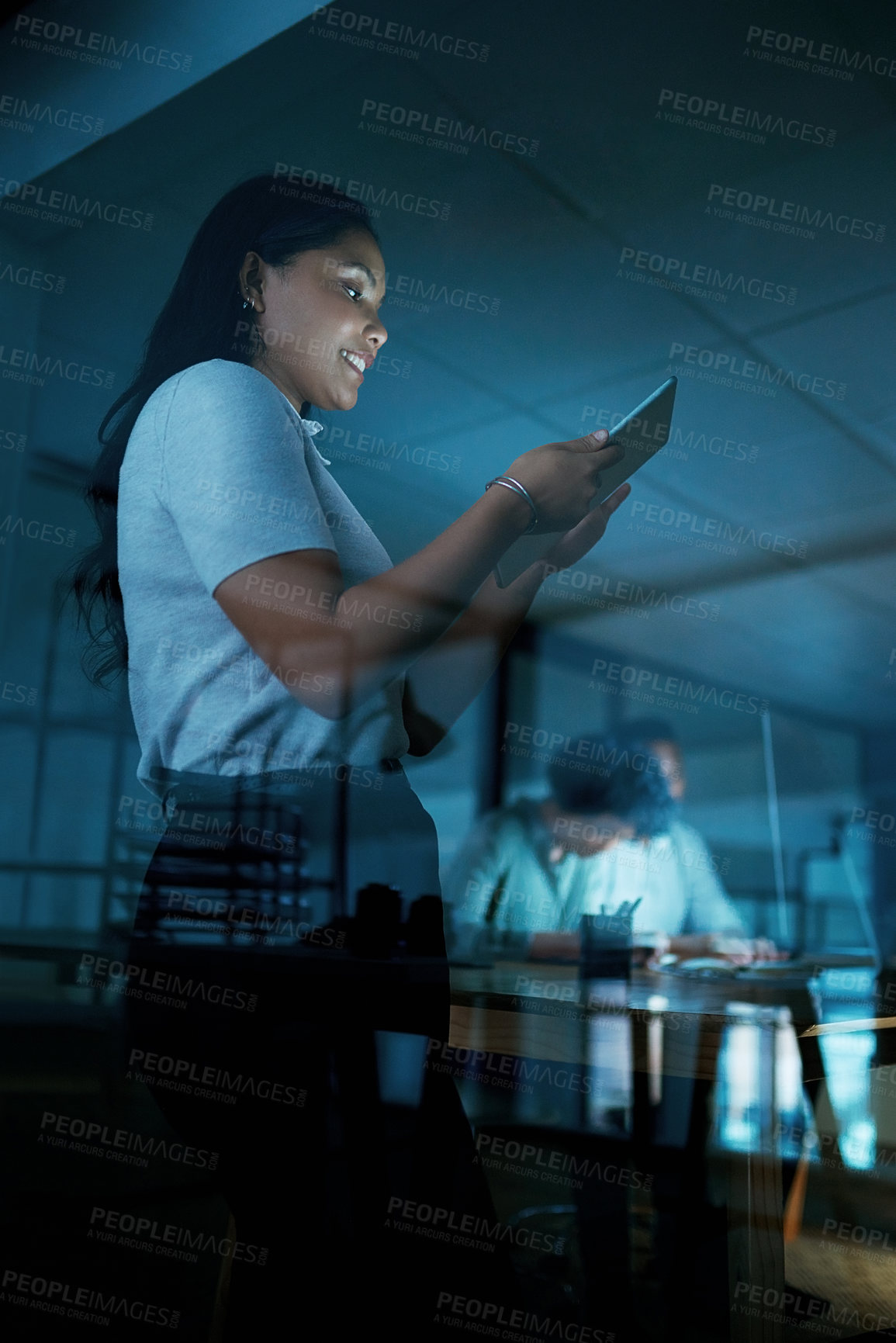 Buy stock photo Shot of a young businesswoman using a digital tablet during a late night at work