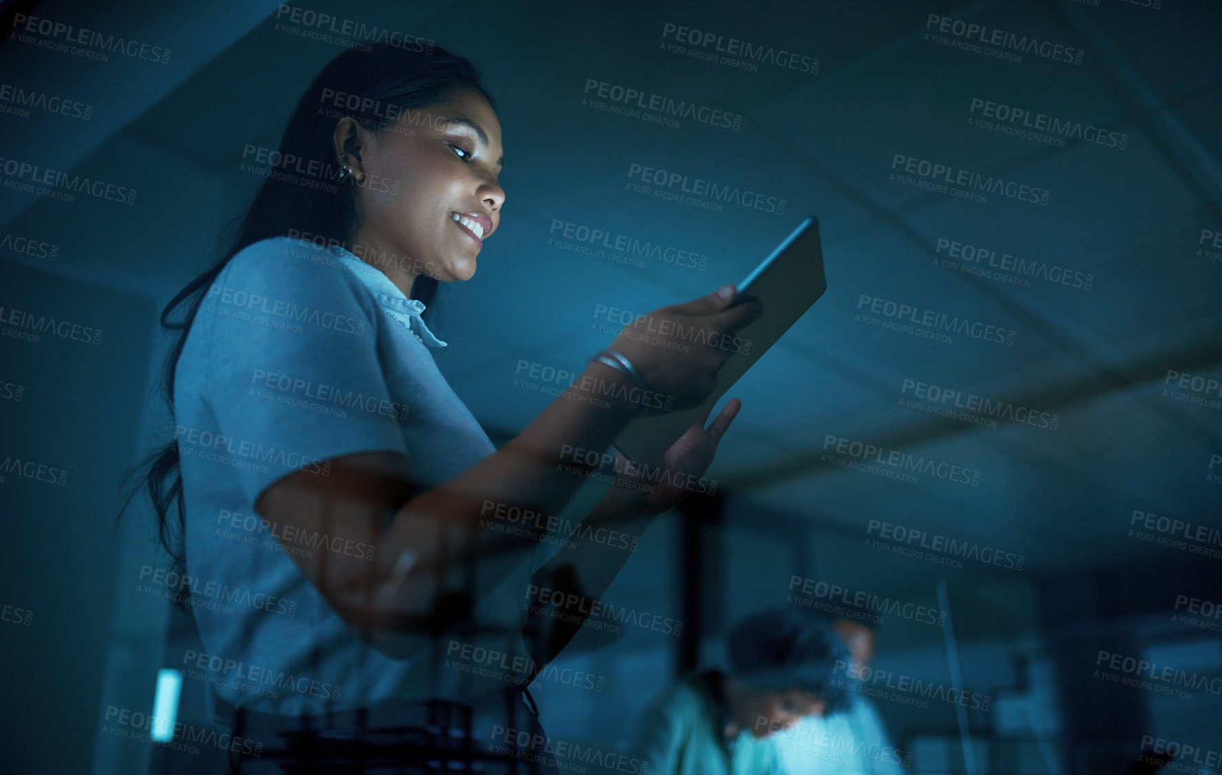 Buy stock photo Shot of a young businesswoman using a digital tablet during a late night at work