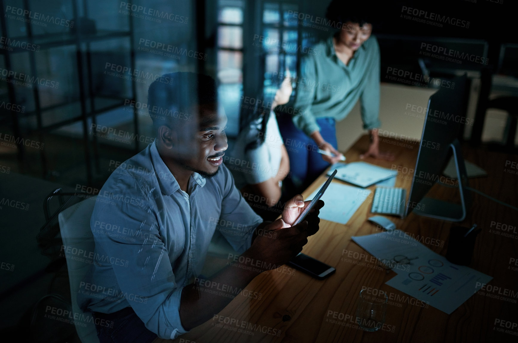 Buy stock photo Shot of a young businessman using a digital tablet during a late night at work