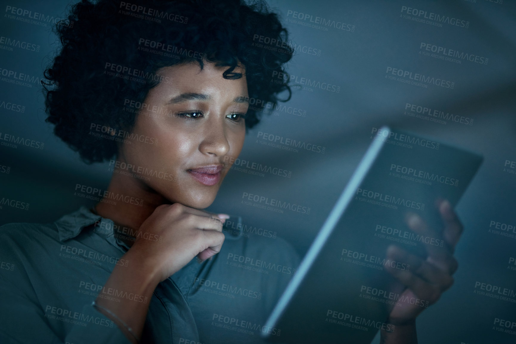 Buy stock photo Shot of a young businesswoman using a digital tablet during a late night at work