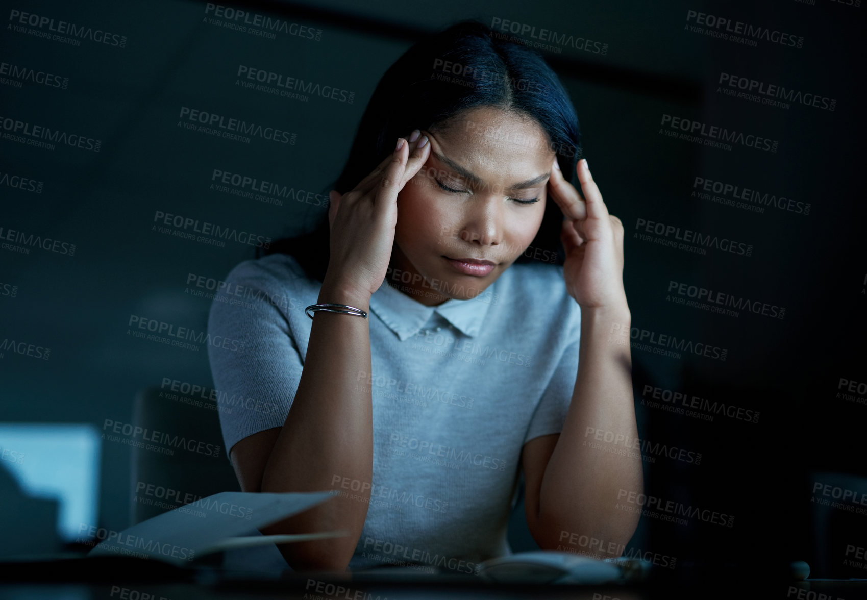 Buy stock photo Shot of a young businesswoman looking stressed while using a computer during a late night at work