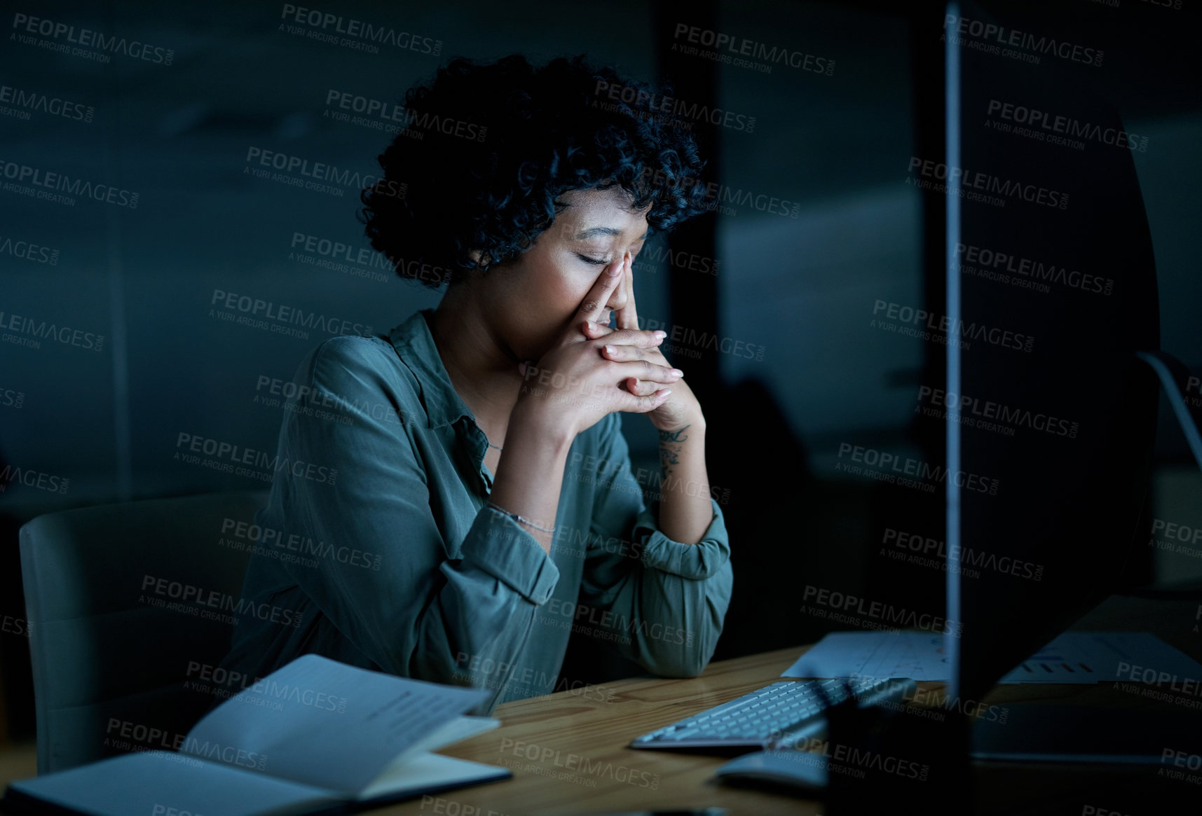 Buy stock photo Shot of a young businesswoman looking stressed while using a computer during a late night at work