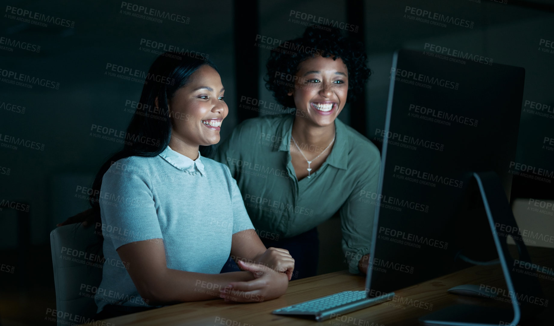 Buy stock photo Shot of two young businesswomen using a computer together during a late night at work