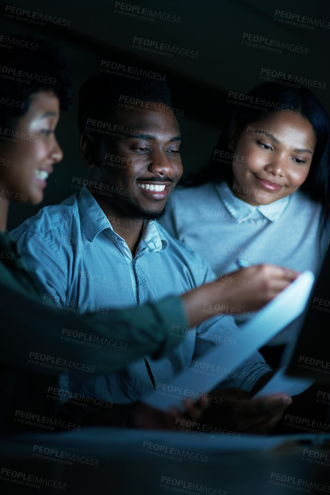 Buy stock photo Shot of a group of young businesspeople using a computer together during a late night at work