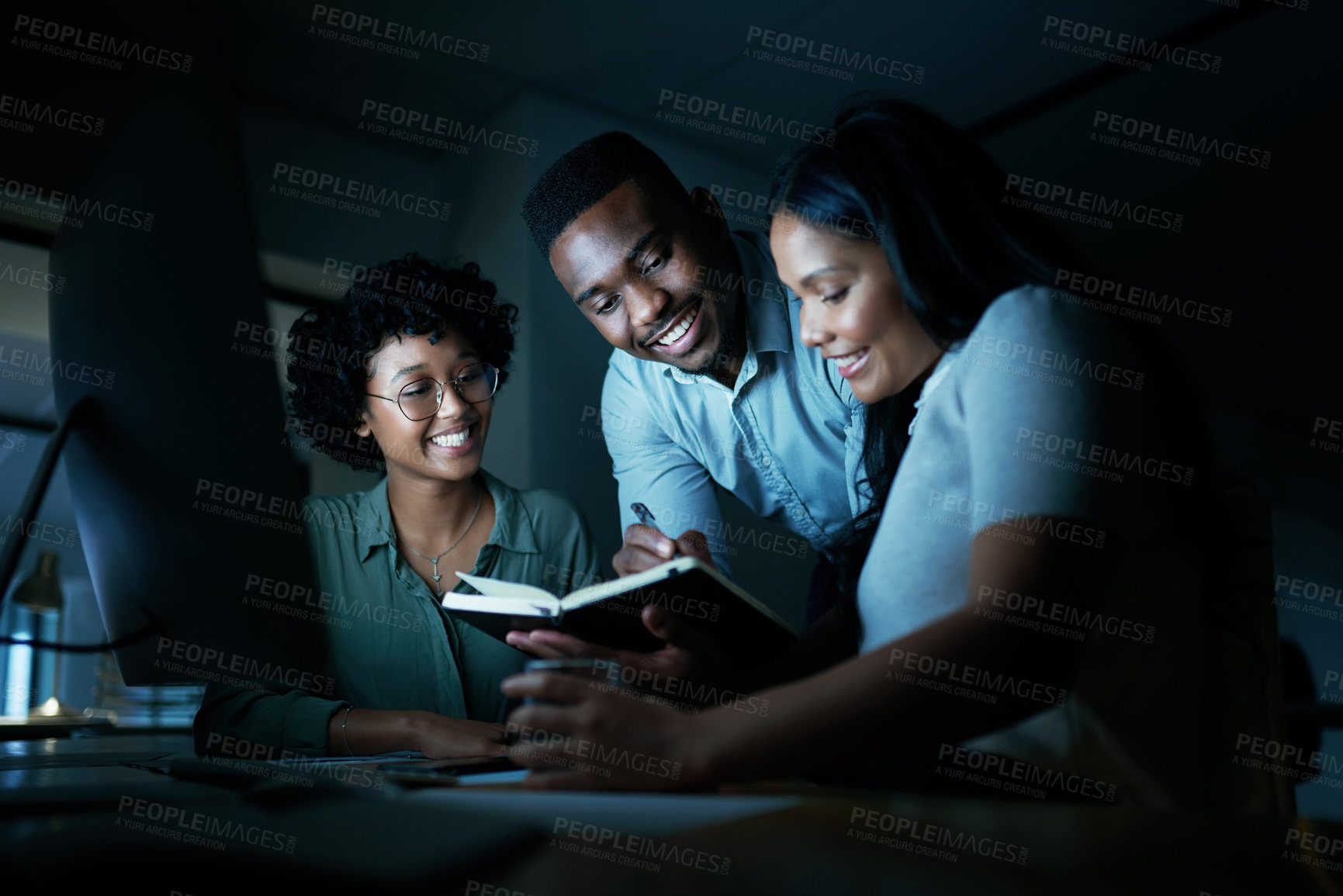 Buy stock photo Shot of a group of young businesspeople using a computer together during a late night at work