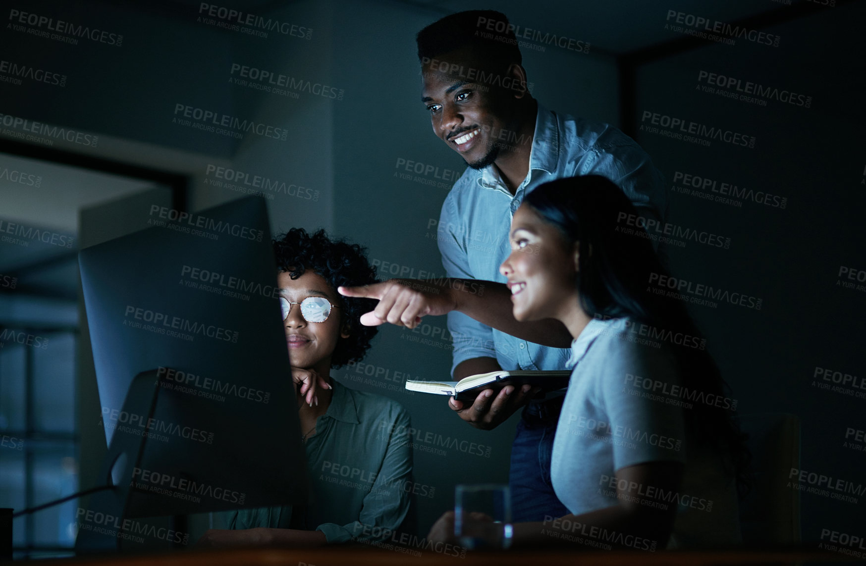 Buy stock photo Shot of a group of young businesspeople using a computer together during a late night at work