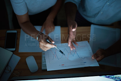 Buy stock photo Shot of unrecognisable businesspeople analysing financial reports during a late night at work