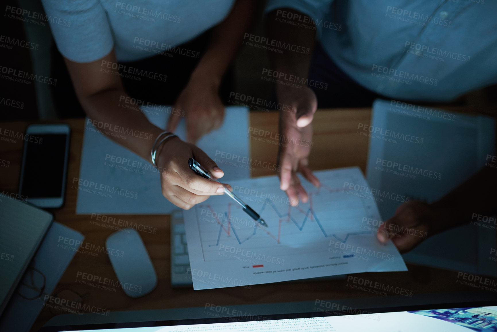 Buy stock photo Shot of unrecognisable businesspeople analysing financial reports during a late night at work