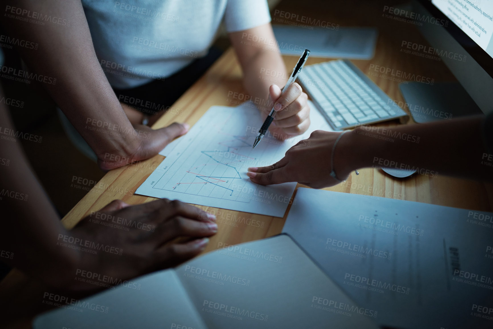 Buy stock photo Shot of unrecognisable businesspeople analysing financial reports during a late night at work