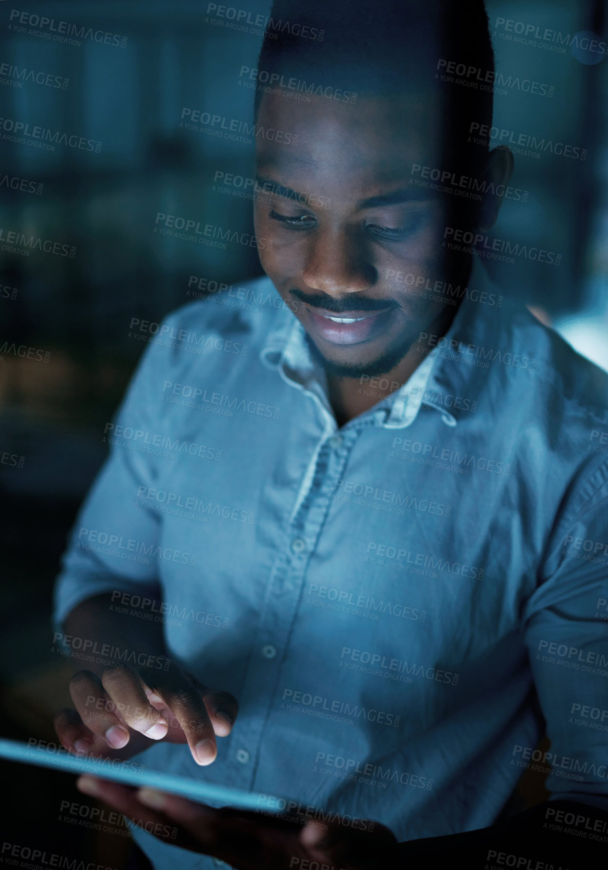 Buy stock photo Shot of a young businessman using a digital tablet during a late night at work