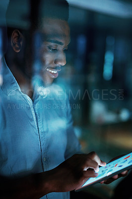 Buy stock photo Shot of a young businessman using a digital tablet during a late night at work