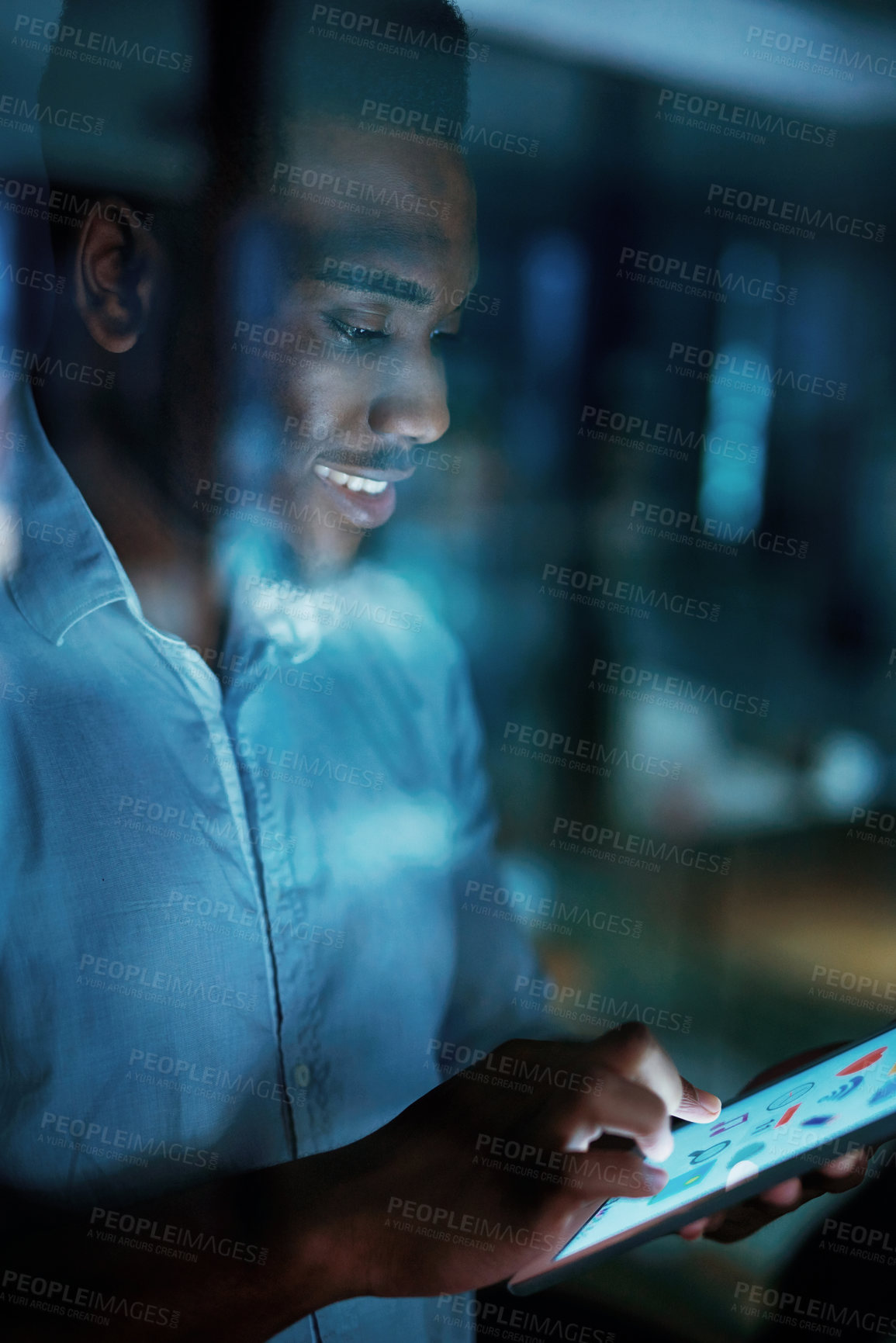 Buy stock photo Shot of a young businessman using a digital tablet during a late night at work