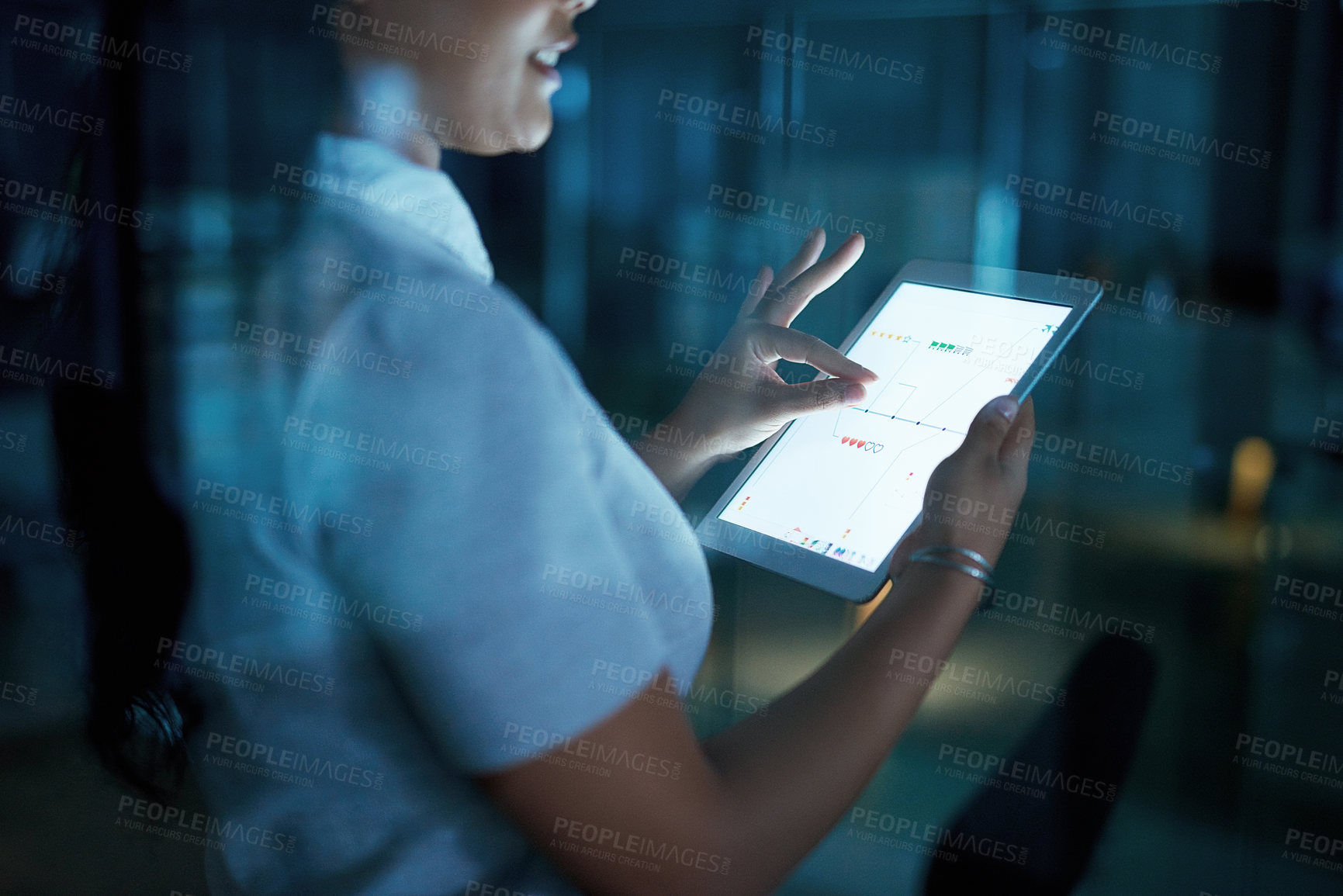 Buy stock photo Shot of an unrecognisable businesswoman using a digital tablet during a late night at work