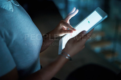 Buy stock photo Shot of an unrecognisable businesswoman using a digital tablet during a late night at work