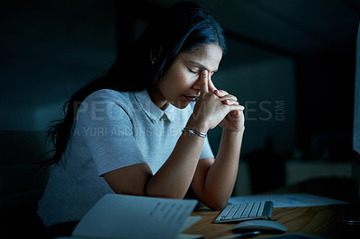 Buy stock photo Shot of a young businesswoman looking stressed while using a computer during a late night at work
