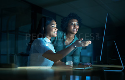 Buy stock photo Shot of two young businesswomen using a computer together during a late night at work