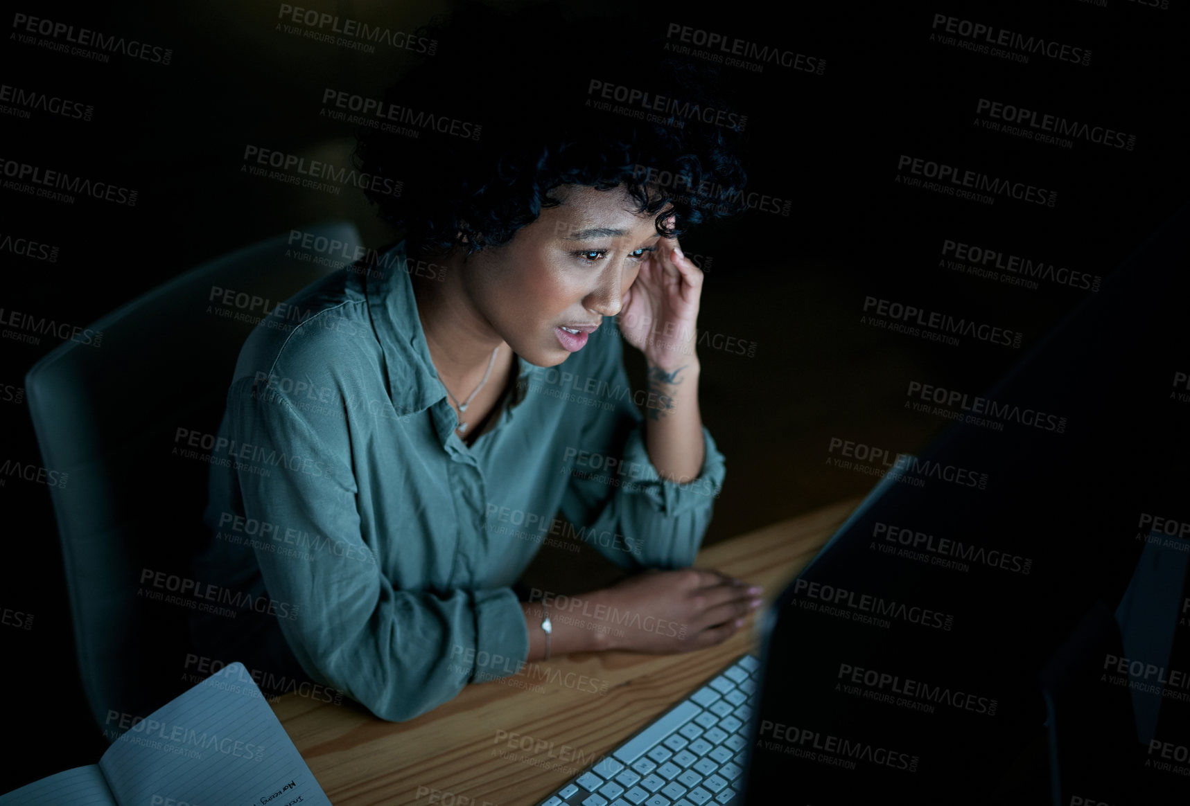 Buy stock photo Shot of a young businesswoman looking stressed while using a computer during a late night at work