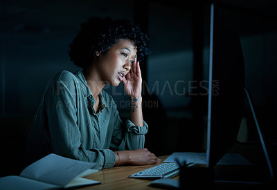 Buy stock photo Shot of a young businesswoman looking stressed while using a computer during a late night at work