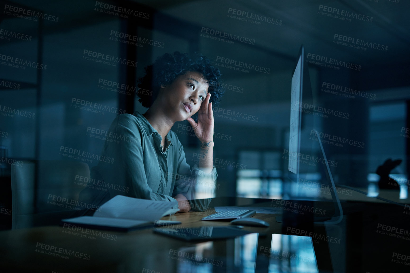 Buy stock photo Shot of a young businesswoman looking stressed while using a computer during a late night at work