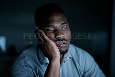 Buy stock photo Shot of a young businessman looking bored during a late night at work