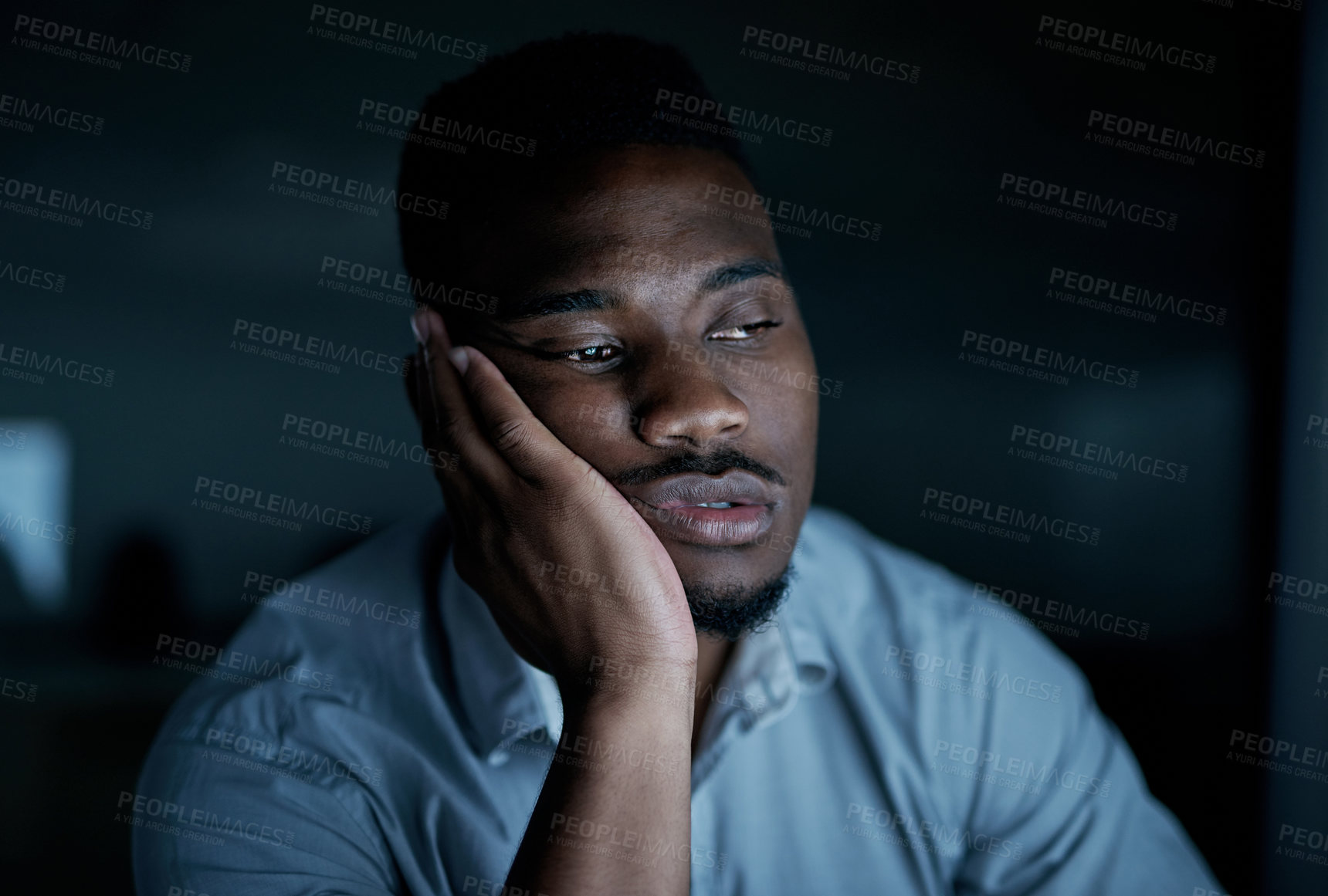 Buy stock photo Shot of a young businessman looking bored during a late night at work