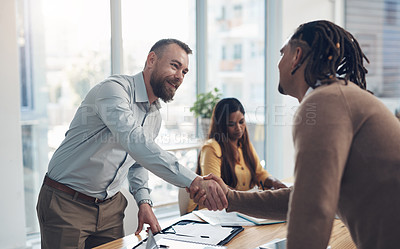 Buy stock photo Cropped shot of two handsome businessmen shaking hands during a meeting in the office during the day