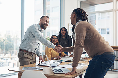 Buy stock photo Cropped shot of two handsome businessmen shaking hands during a meeting in the office during the day