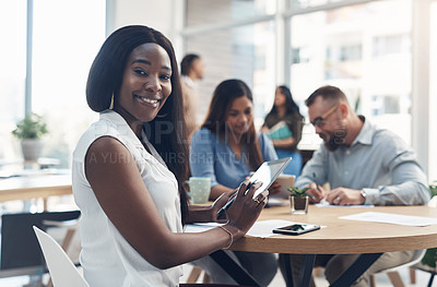 Buy stock photo Cropped portrait of an attractive young businesswoman sitting and using a tablet while her coworkers work behind her