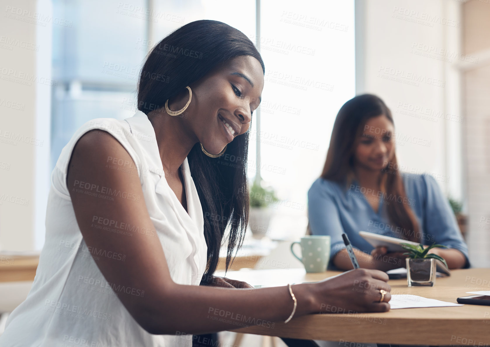 Buy stock photo Cropped shot of an attractive young businesswoman sitting in the office and signing paperwork while her colleagues work behind her