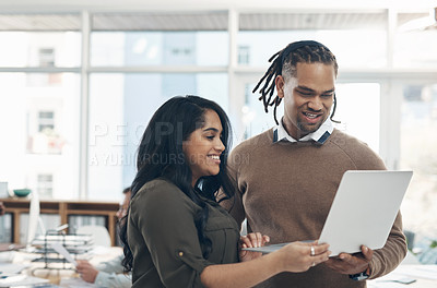 Buy stock photo Cropped shot of two young businesspeople standing together and using a laptop in the office