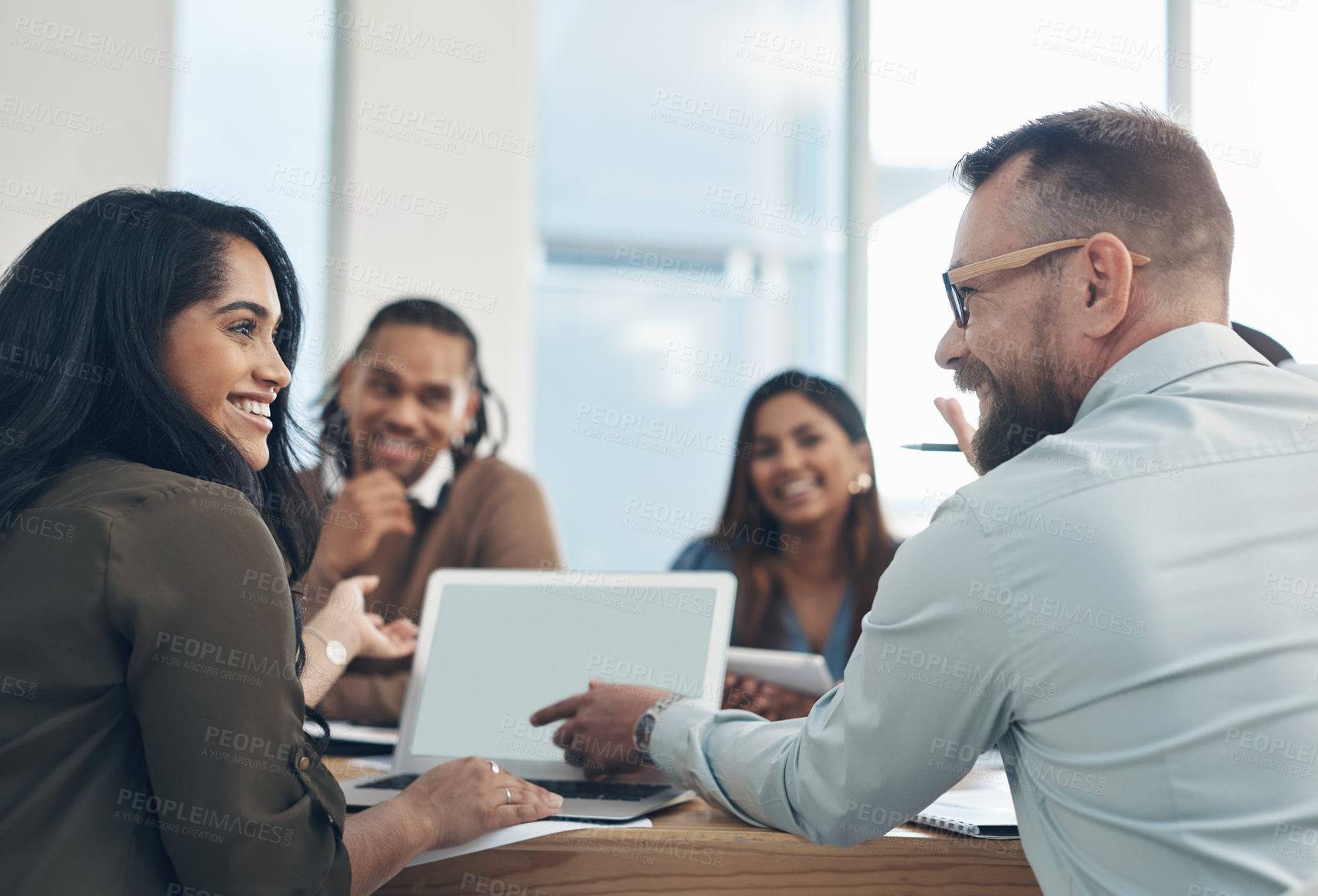 Buy stock photo Cropped shot of a diverse group of businesspeople sitting together and using a laptop during a meeting in the office