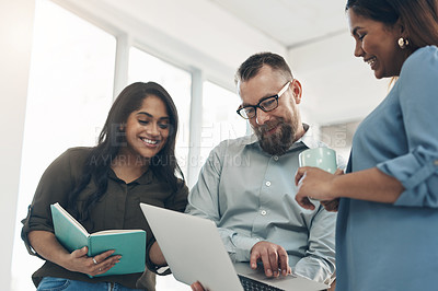 Buy stock photo Cropped shot of a diverse group of businesspeople standing together and using a laptop during a discussion in the office