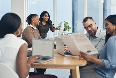 Buy stock photo Cropped shot of two young businesspeople using a computer in the office while their colleagues work in the foreground