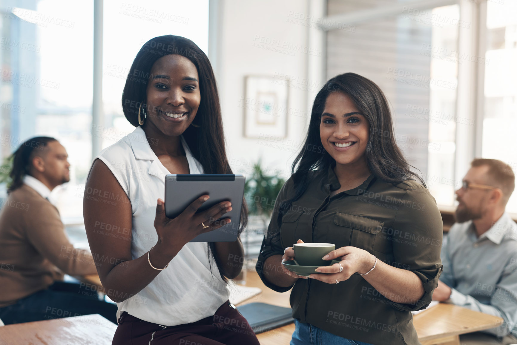 Buy stock photo Cropped portrait of two attractive businesswomen using a tablet in the office while their colleagues work behind them