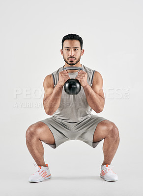 Buy stock photo Studio portrait of a muscular young man exercising with a kettlebell against a white background