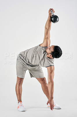 Buy stock photo Studio shot of a muscular young man exercising with a kettlebell against a white background