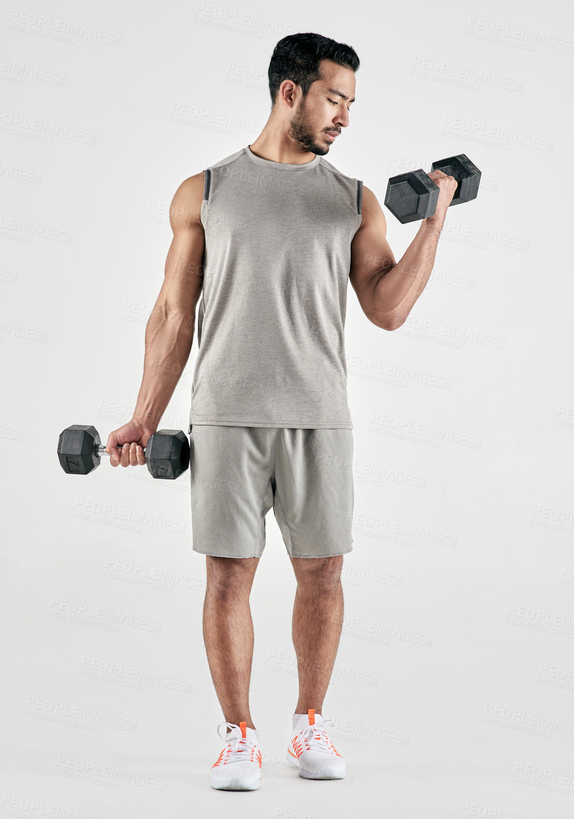 Buy stock photo Studio shot of a muscular young man exercising with dumbbells against a white background