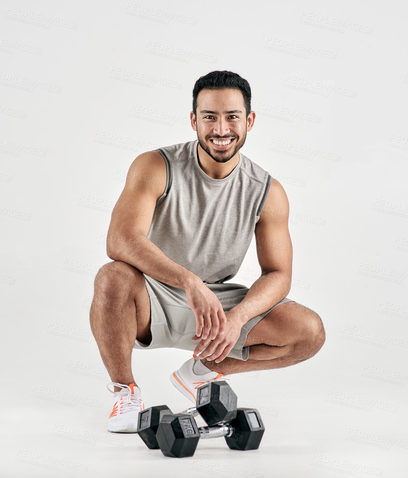 Buy stock photo Studio portrait of a muscular young man posing with dumbbells against a white background