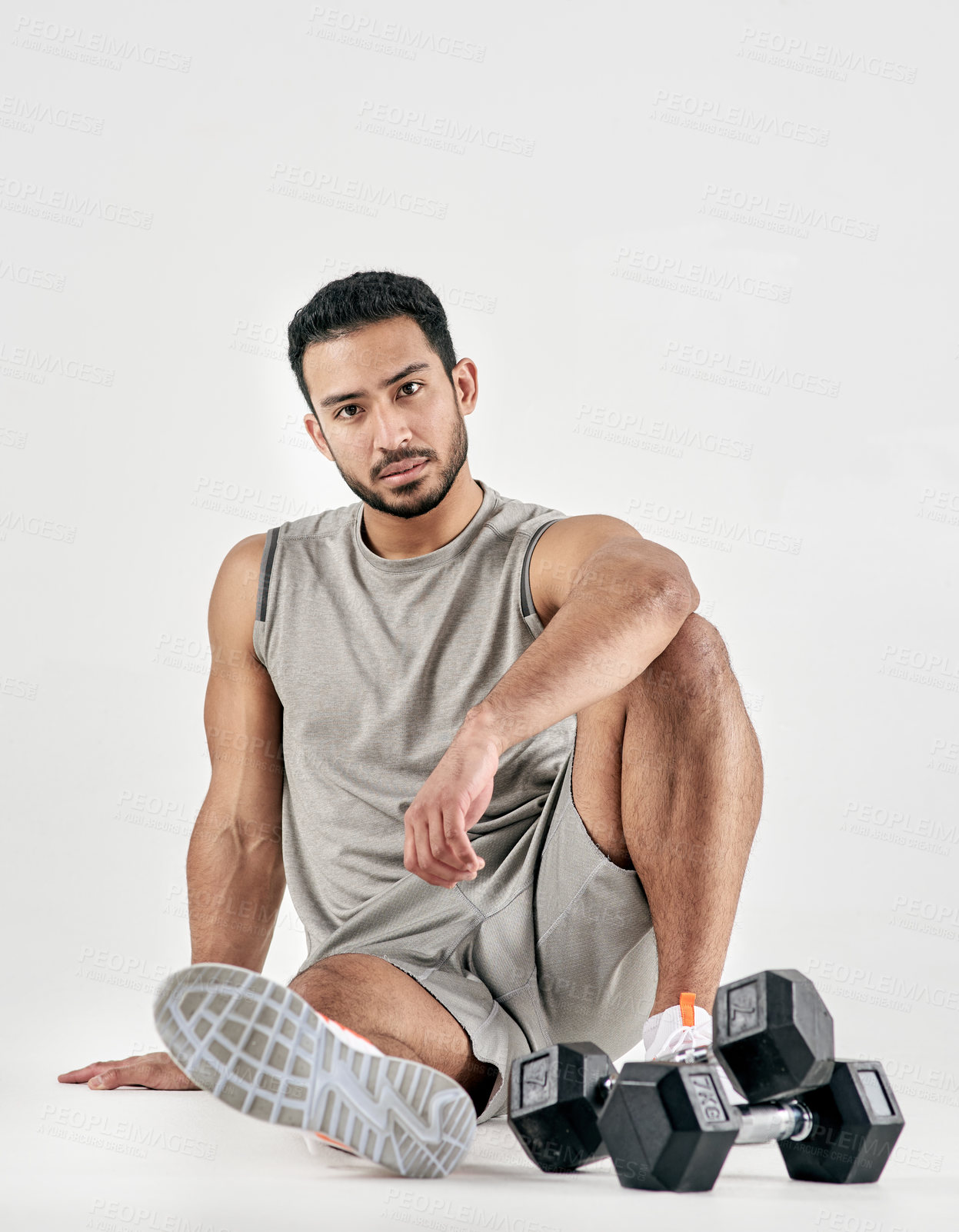 Buy stock photo Studio portrait of a muscular young man posing with dumbbells against a white background