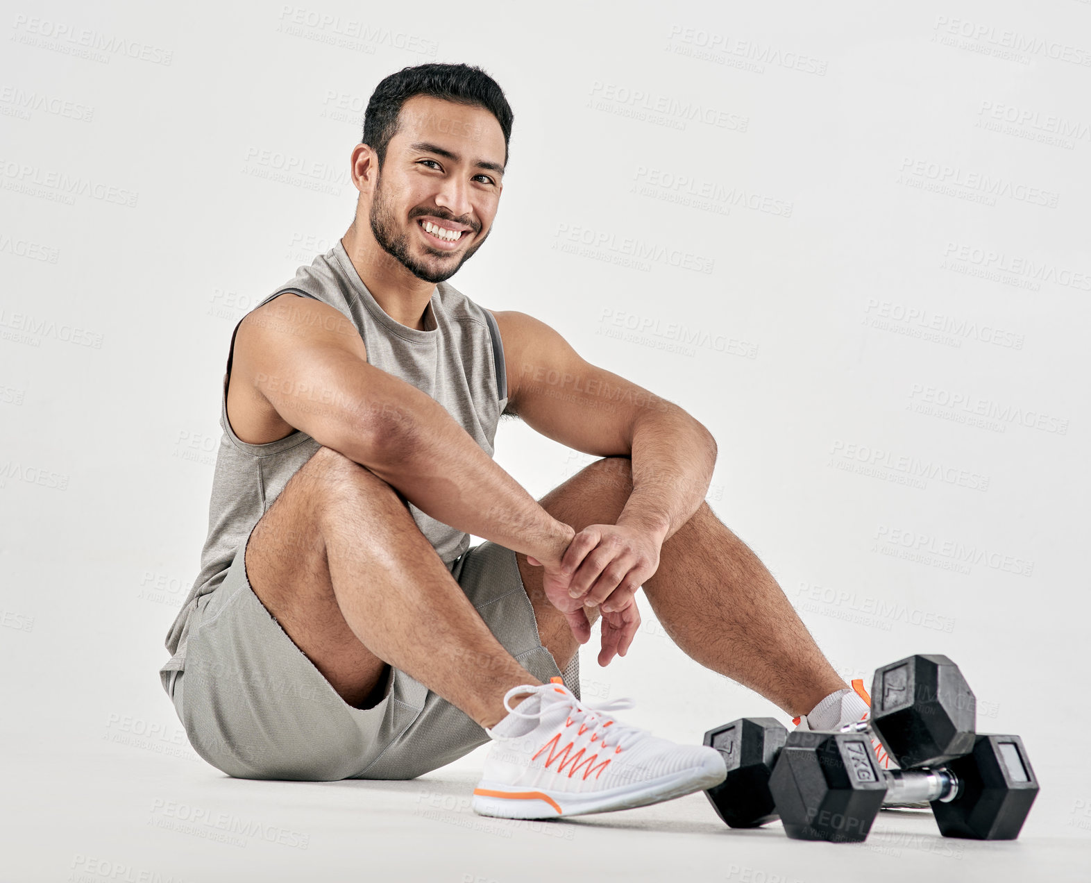 Buy stock photo Studio portrait of a muscular young man posing with dumbbells against a white background