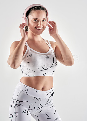 Buy stock photo Studio portrait of a sporty young woman wearing headphones against a white background