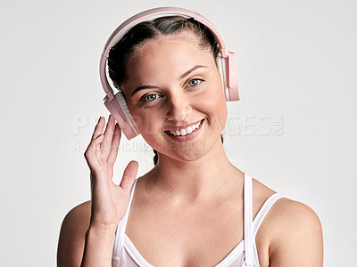 Buy stock photo Studio portrait of a sporty young woman wearing headphones against a white background