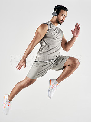 Buy stock photo Studio shot of a sporty young man wearing headphones and jumping against a white background