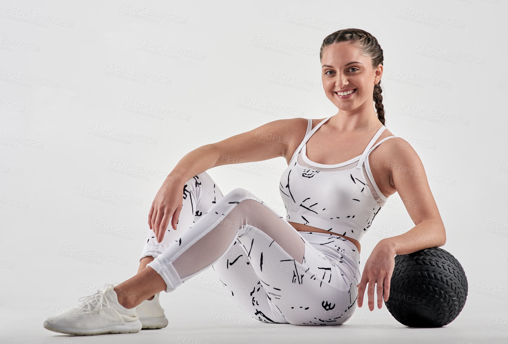 Buy stock photo Studio portrait of a sporty young woman posing with an exercise ball against a white background