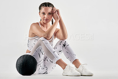 Buy stock photo Studio portrait of a sporty young woman posing with an exercise ball against a white background