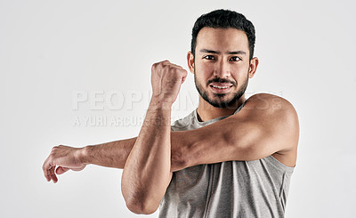Buy stock photo Studio portrait of a muscular young man stretching his arms against a white background